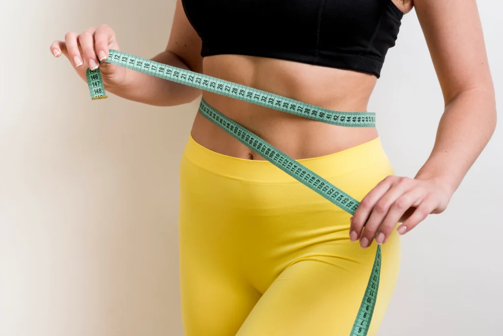 Image of a fitness woman with measurement tape, dedicated to achieving her fat loss goals.