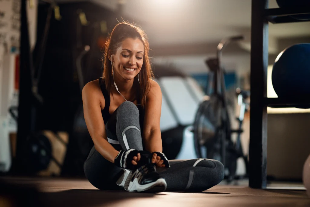 Image of a young and happy sportswoman getting ready for her workout at the fitness center, tying her shoelaces with determination.